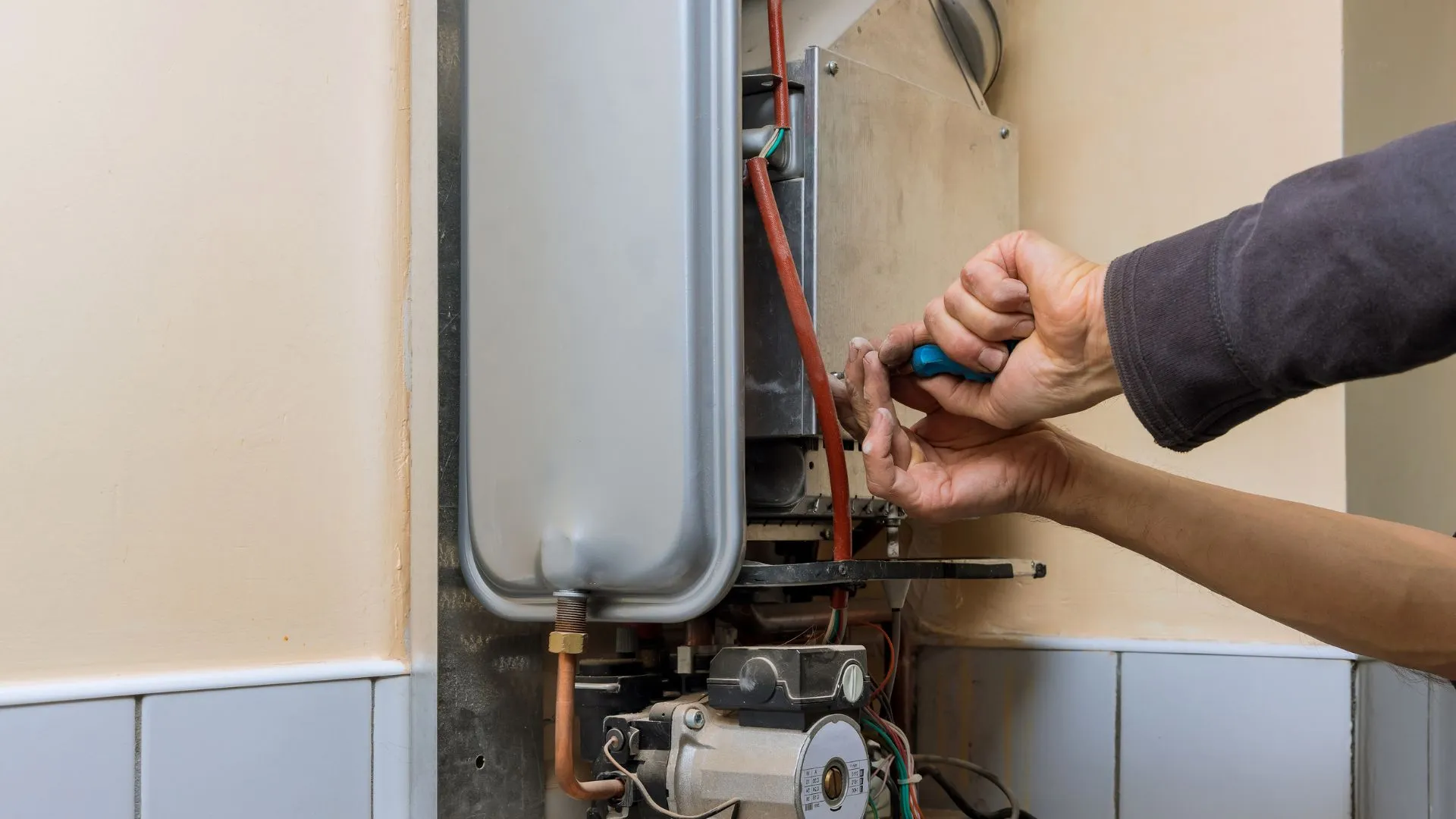 icensed JK Plumbing technician inspecting a gas water heater with upper and lower seismic straps in a San Francisco garage