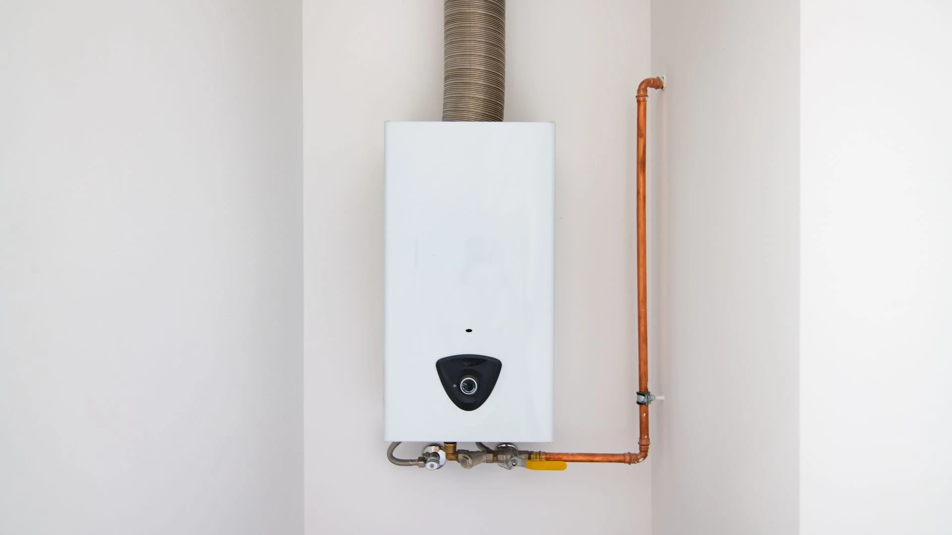 JK Plumbing technician servicing a wall-mounted tankless water heater in San Francisco