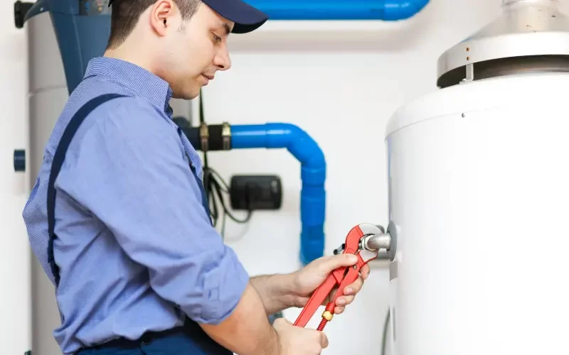 Plumber tightening water heater fitting with wrench
